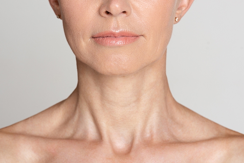 Skin care. Half face portrait of mature woman with wrinkled neck, grey background, crop