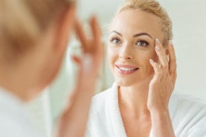 woman touching face looking in mirror