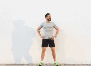Fit Man standing against a wall with hands on waist